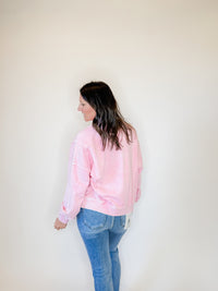 Women's pink Henley pullover sweatshirt with a vintage washed finish, balloon sleeves, and a relaxed fit. Features a button-up neckline and ribbed hem for a stylish and cozy look. Perfect for casual wear, layering, and effortless everyday fashion. Paired with classic blue jeans for a trendy, laid-back outfit.