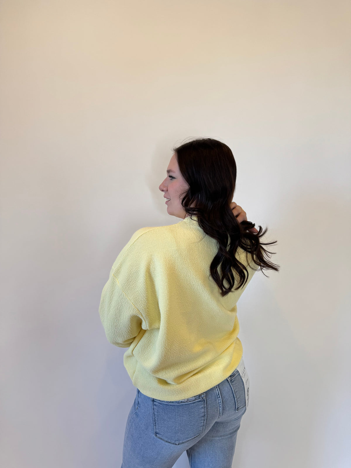 Women's pastel yellow waffle knit sweatshirt with a relaxed fit, long sleeves, and ribbed cuffs. Styled with light-wash straight-leg jeans and casual sneakers for a trendy and cozy everyday look. Perfect for layering in fall, winter, and spring fashion.