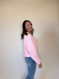 Women's pink crewneck sweatshirt with a textured knit design, long sleeves, and a relaxed fit. Styled with classic blue jeans for a casual and cozy everyday outfit. Perfect for layering in fall, winter, and spring fashion. Soft and comfortable pullover sweater for effortless style.