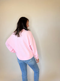 Women's pink crewneck sweatshirt with a textured knit design, long sleeves, and a relaxed fit. Styled with classic blue jeans for a casual and cozy everyday outfit. Perfect for layering in fall, winter, and spring fashion. Soft and comfortable pullover sweater for effortless style.