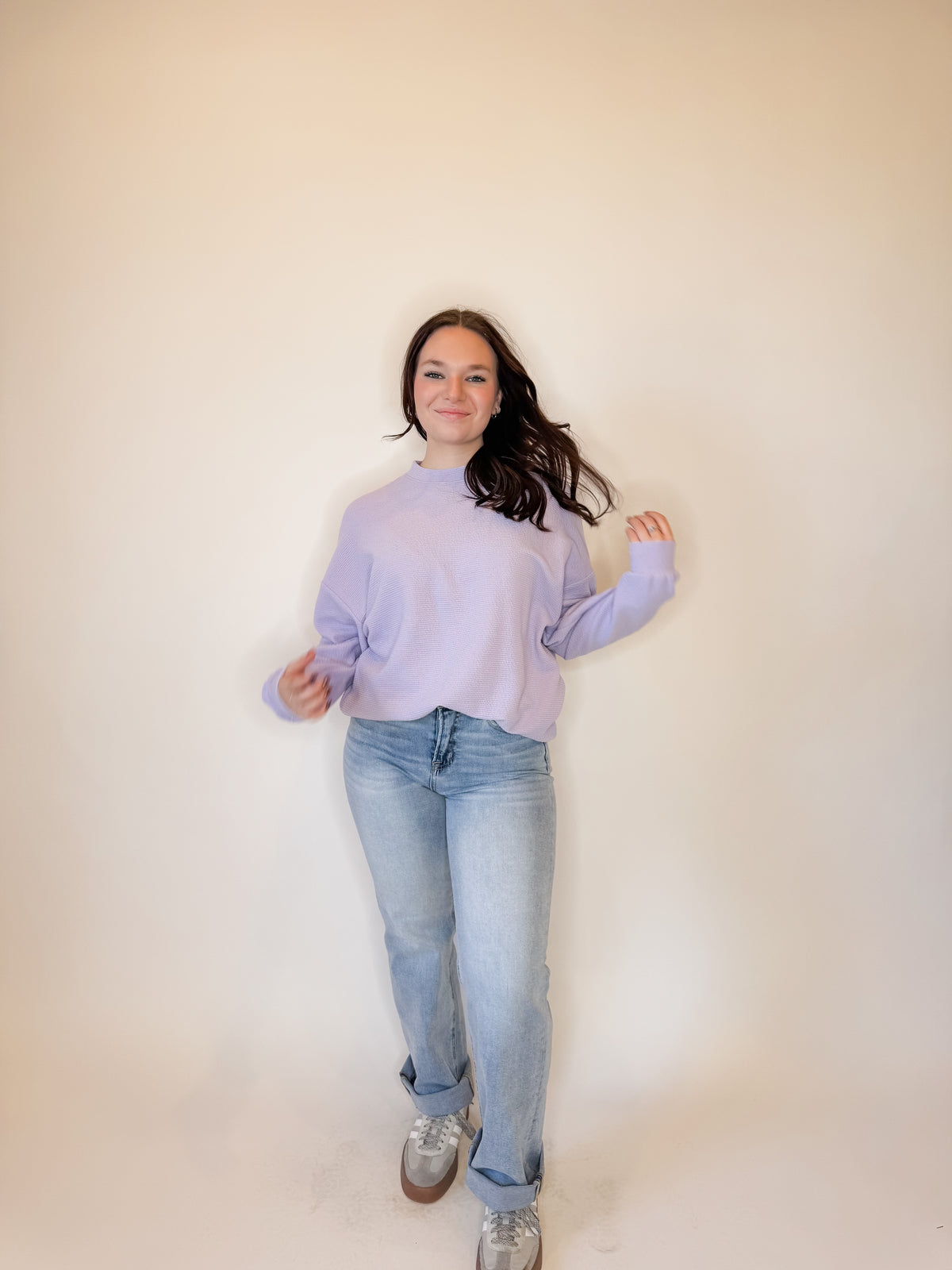 Women's lavender purple oversized sweatshirt with a textured waffle knit design, featuring a relaxed fit and long sleeves. Styled with light-wash straight-leg jeans and casual sneakers for a trendy, effortless look. Perfect for cozy everyday wear, layering, and casual fashion in fall, winter, and spring.